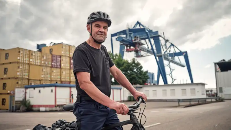 JobRadler steht am Containerhafen und blickt selbstbewusst in die Kamera