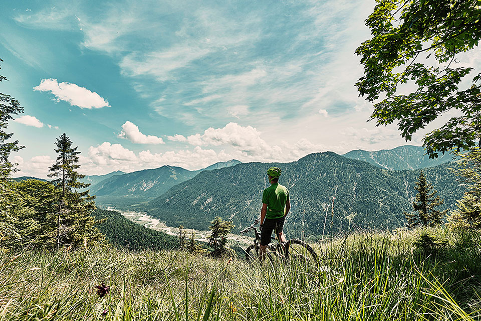 Mountainbiker auf Bergwiese mit Aussicht ins Tal