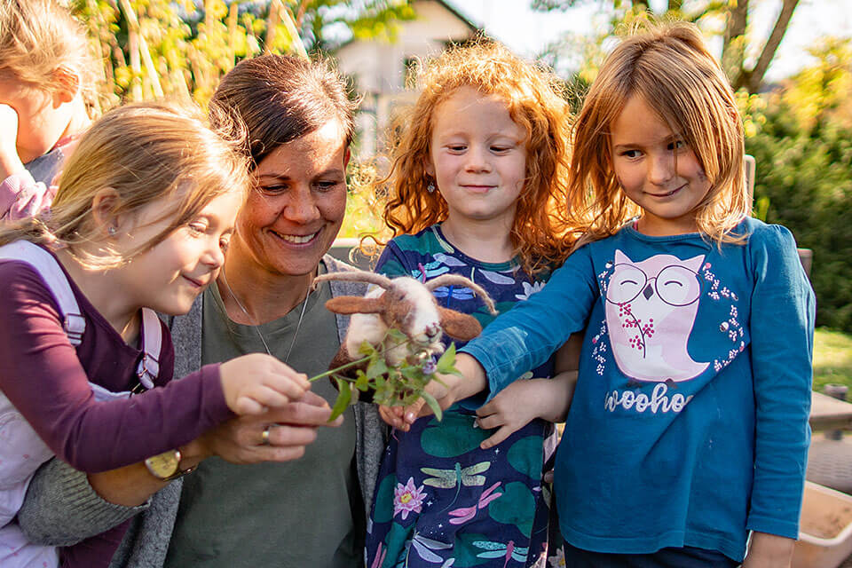 Kinder im Naturpark Kindergarten spielen mit Pflanzen und einer Handpuppe